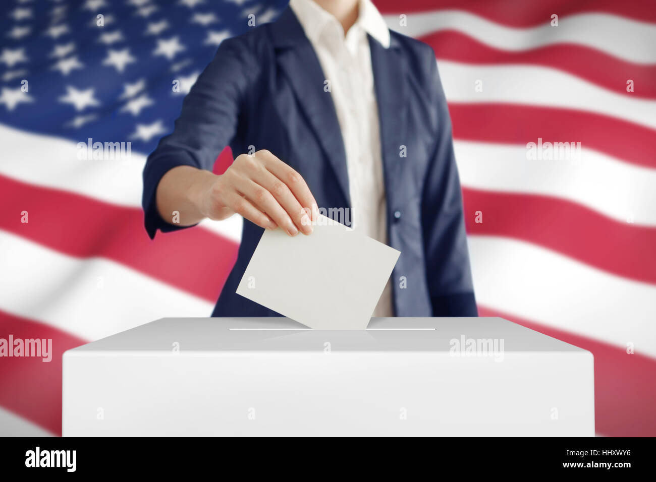 Woman putting a ballot into a voting box with USA flag on background. Stock Photo