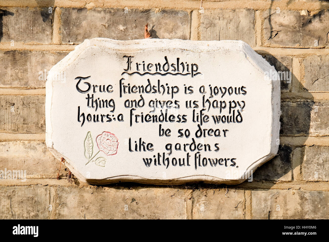 A stone tablet on the side of a cottage displays a quote about frienship Stock Photo