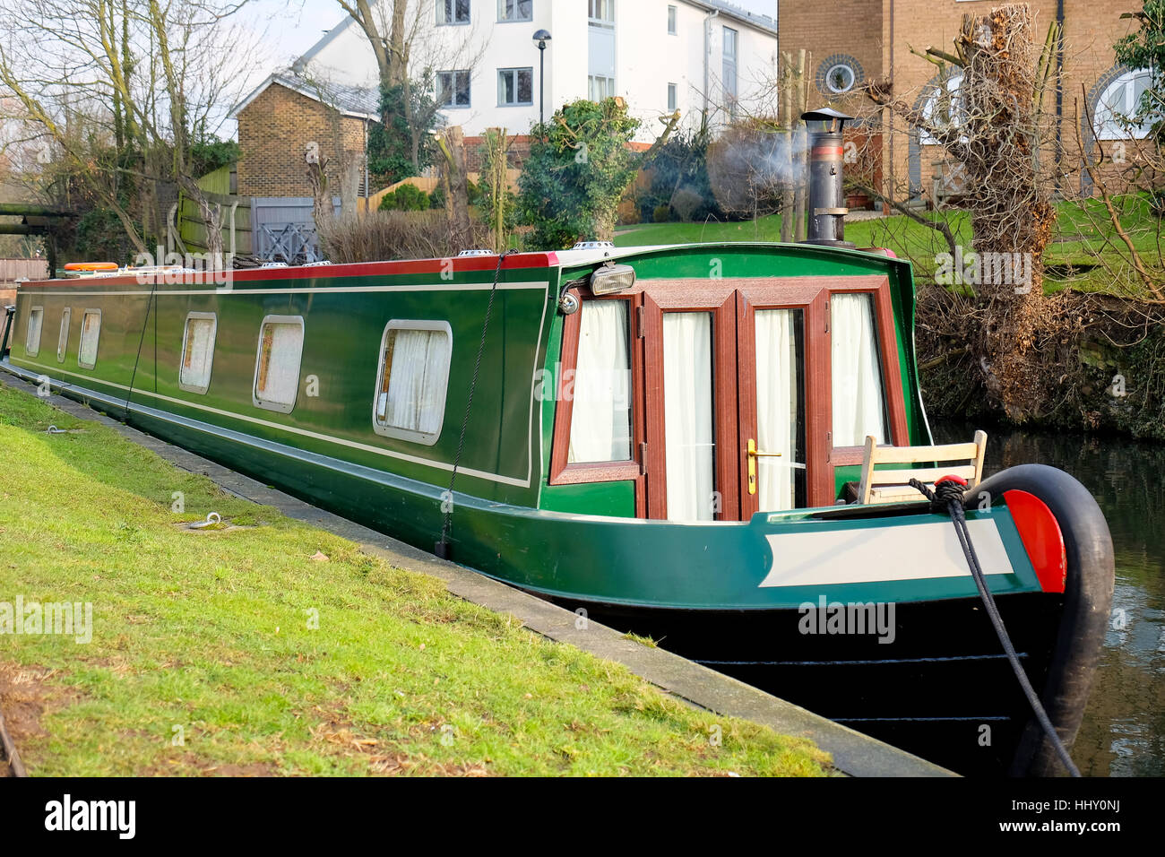 A green barge with smoking chimney moored on a canal in Hertford, England Stock Photo