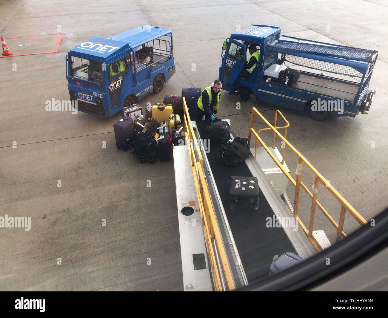 Airport workers unload luggage from the aircraft after landing at the Charles de Gaulle Airport in Paris, France. Stock Photo