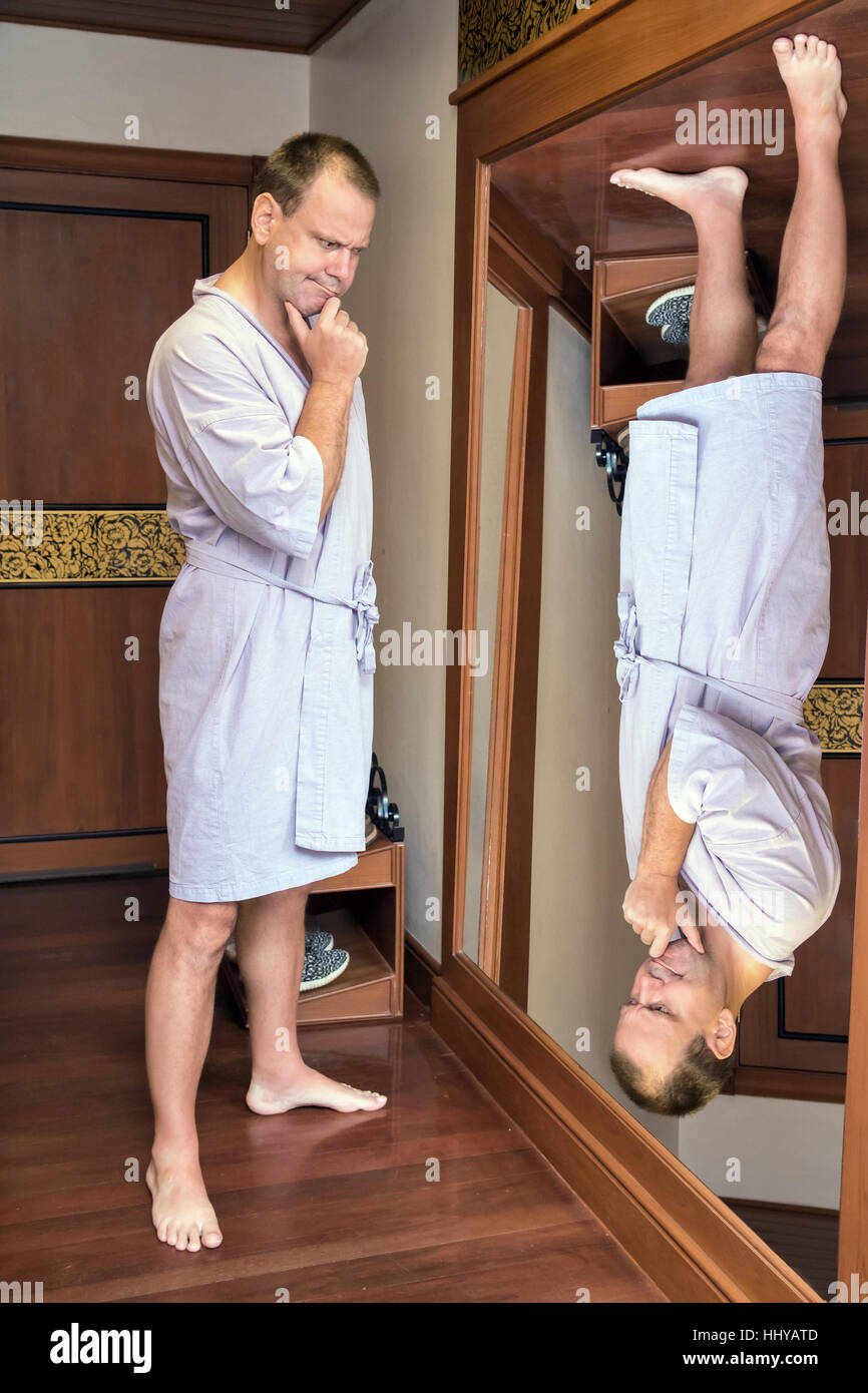 a man in a robe meditating when looking reverse reflection in the mirror Stock Photo