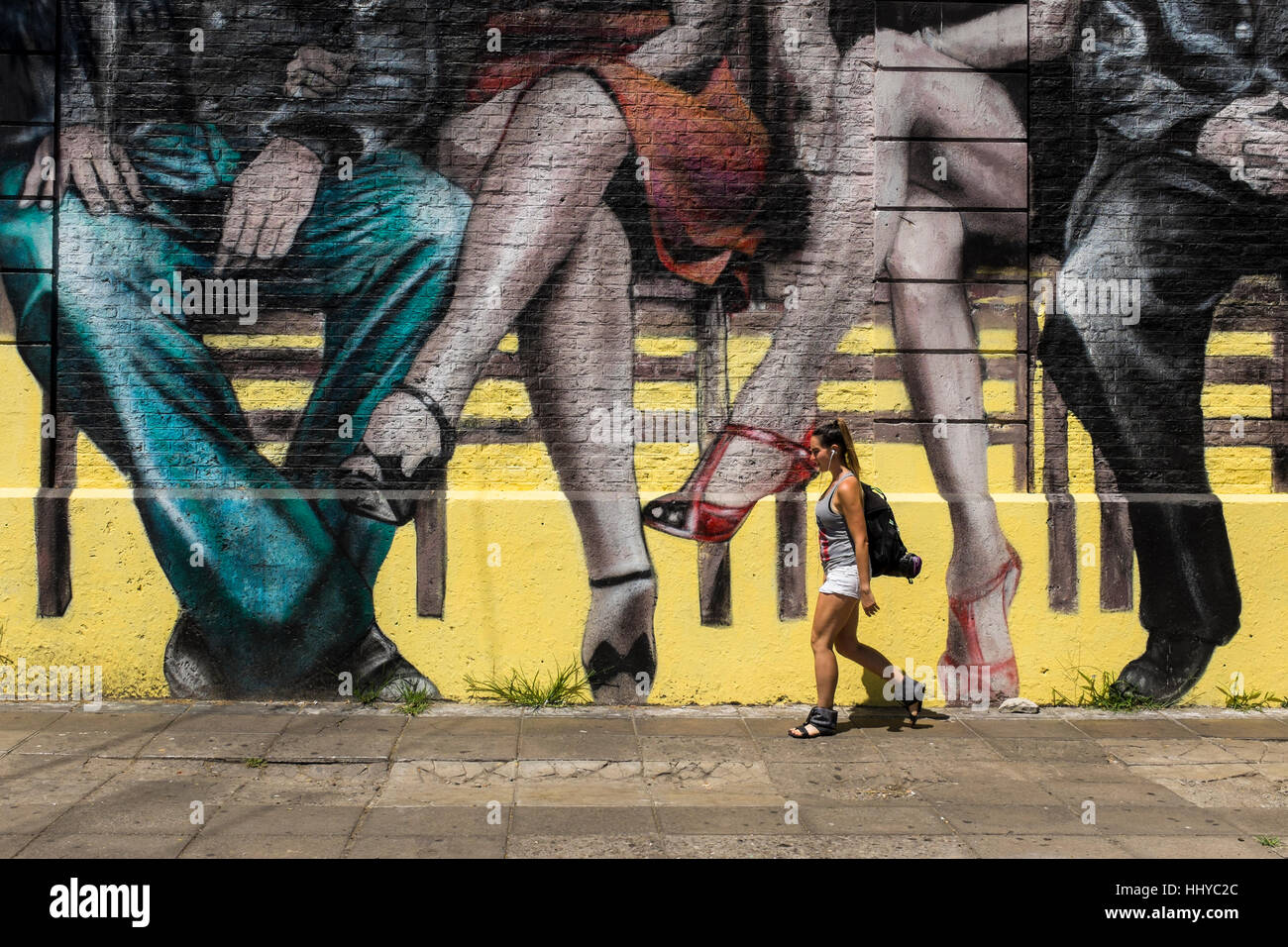 A woman walks past a city mural depicting sitting couples, Buenos Aires city, Argentina. Stock Photo