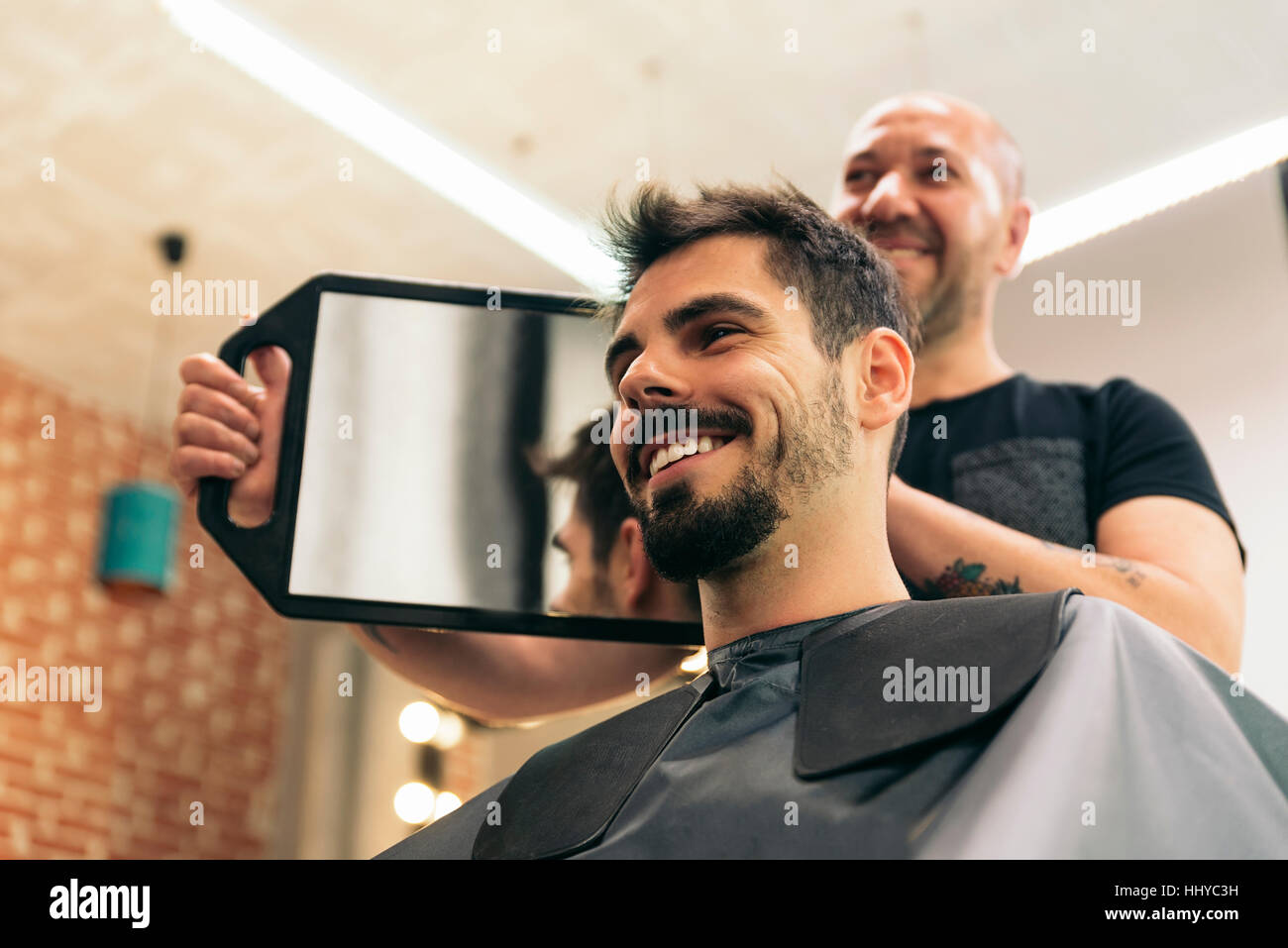 Hairdresser showing his work through the mirror Stock Photo Alamy