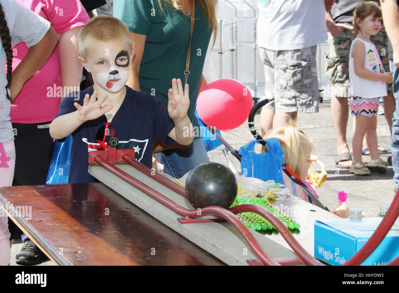 Young boy with face paint rolls a ball down a track in a Roller Bowler
