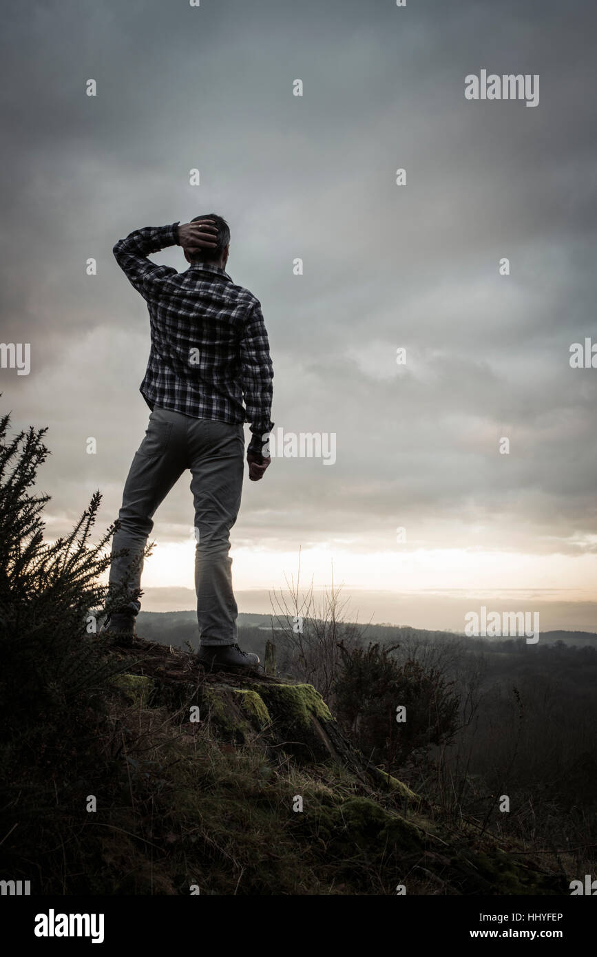 A man watching the last rays of sunlight, as more uncertain weather conditions move in. Stock Photo