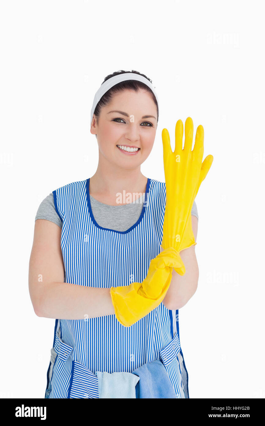 Cleaner woman putting on yellow gloves in the white background Stock