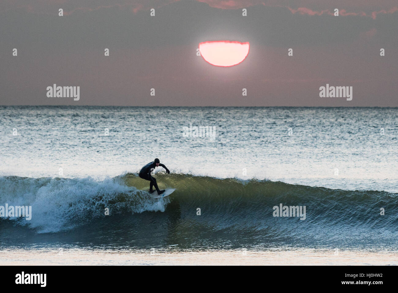 Aberystwyth Wales UK, Saturday 21 January 2017  UK weather: After a freezing cold night, with temperatures well below zero, surfers enjoy the waves at sunset at the end of a fine day of warm sunshine  in Aberystwyth on the Cardigan Bay coast of West Wales    photo  Keith Morris / Alamy Live News Stock Photo