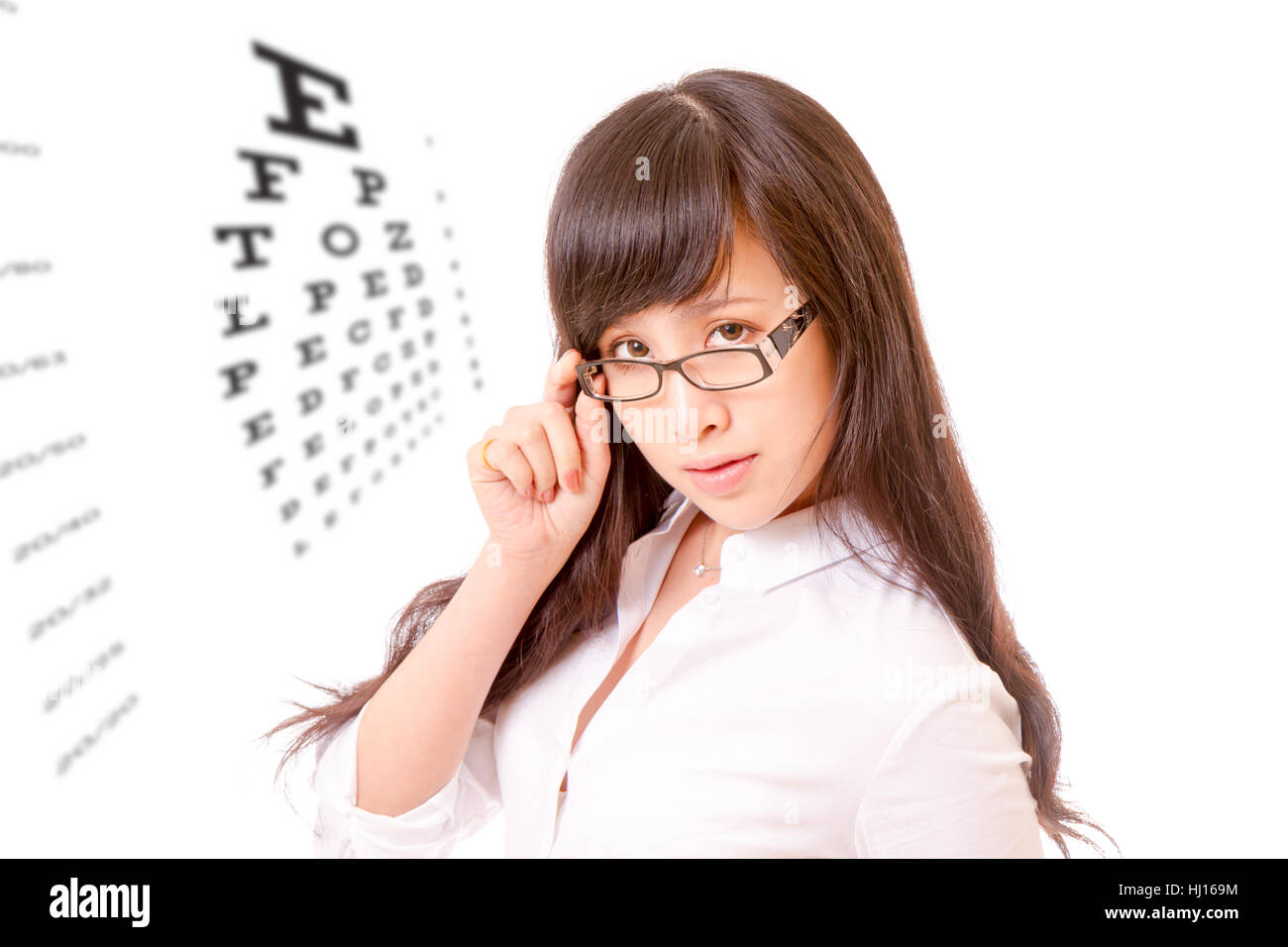 Chinese woman peering over the top of her spectacles, with eyesight test chart Stock Photo