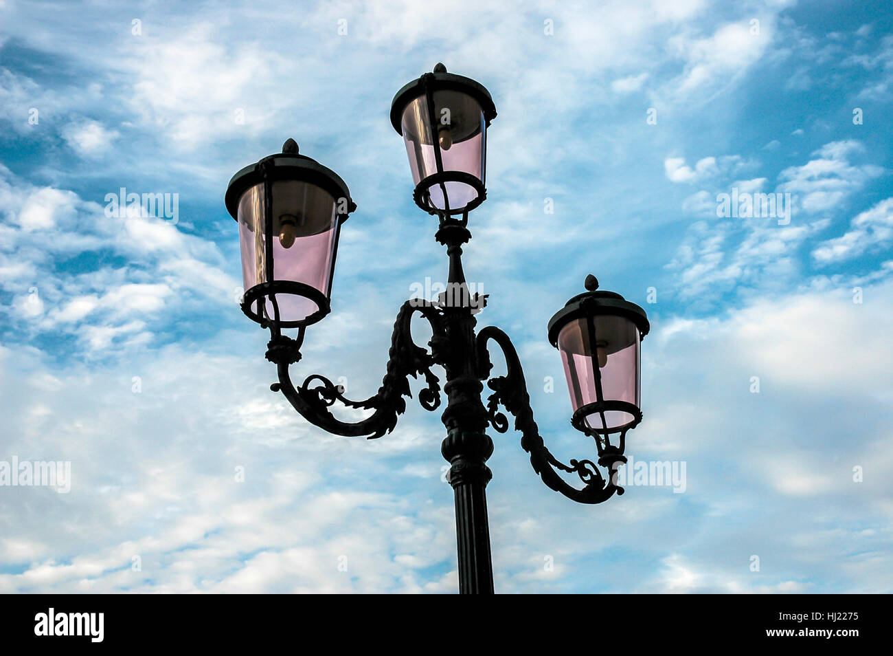 Cast iron street lamp in Venice in front of blue sky with clouds Stock