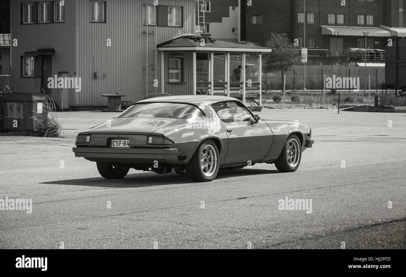 Kotka, Finland - July 16, 2016: Red 1976 Chevrolet Camaro Sport goes down the street in European town, rear view, monochrome toned photo, retro style Stock Photo