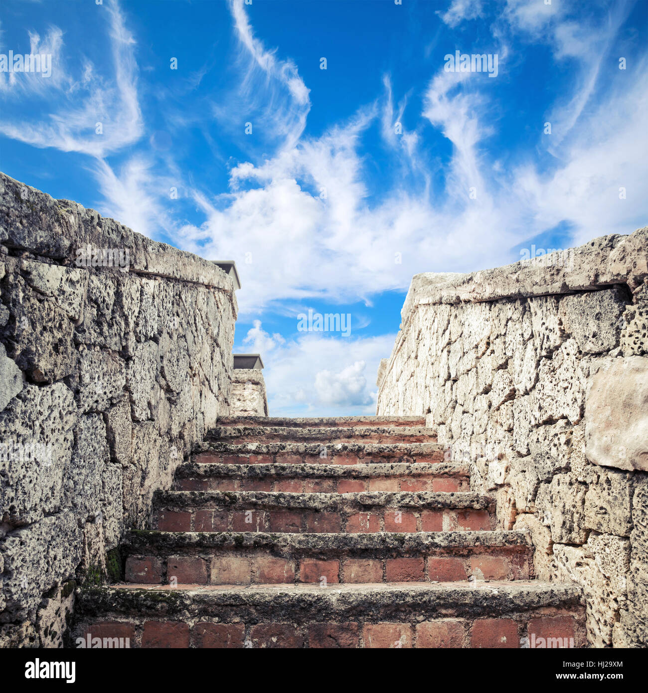 Ancient stone stairway goes up under blue cloudy sky background Stock Photo