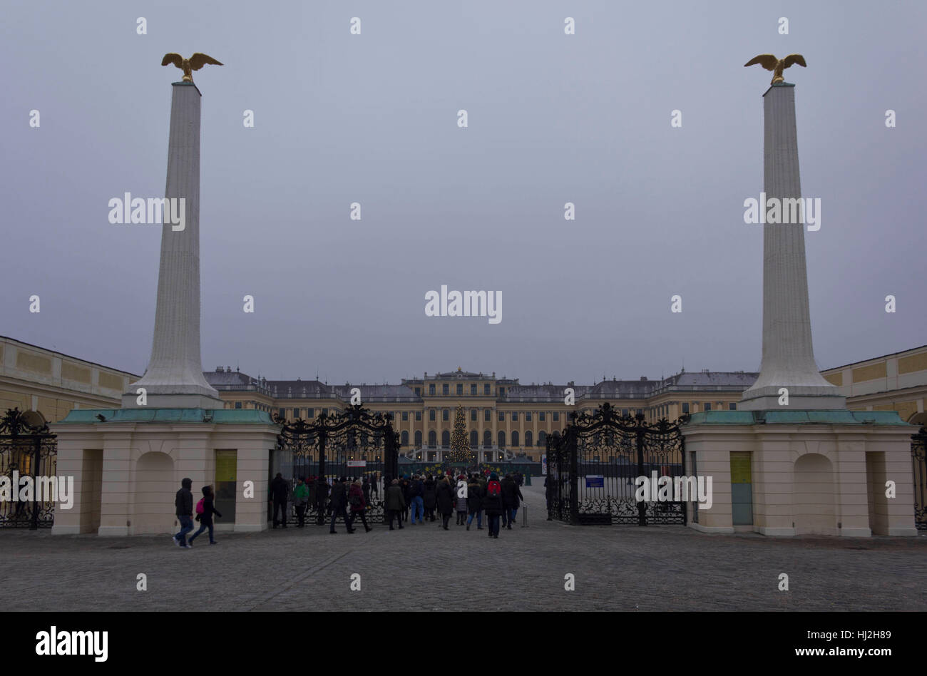 VIENNA, AUSTRIA - JANUARY 2 2016: View from the street of Schonbrunn Palace in Vienna in a foggy winter day, with people and a Christmas tree in the m Stock Photo