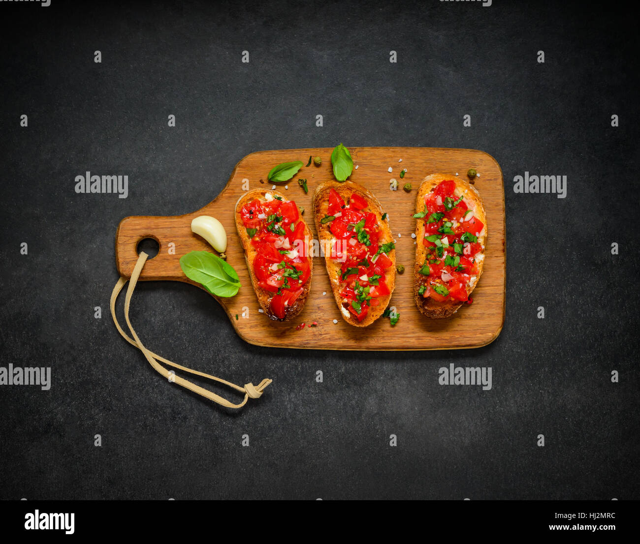 Bruschetta Italian Food or Mediterranean Cuisine with Tomato and Basil on Wooden Chopping Board Stock Photo