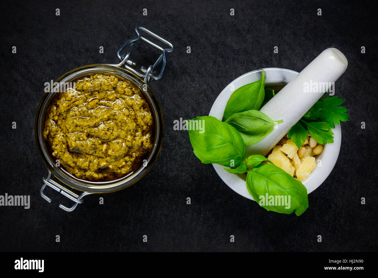 Top View of Green Pesto with Pestle and Mortar with Basil, Cheese and Pine Nuts Stock Photo