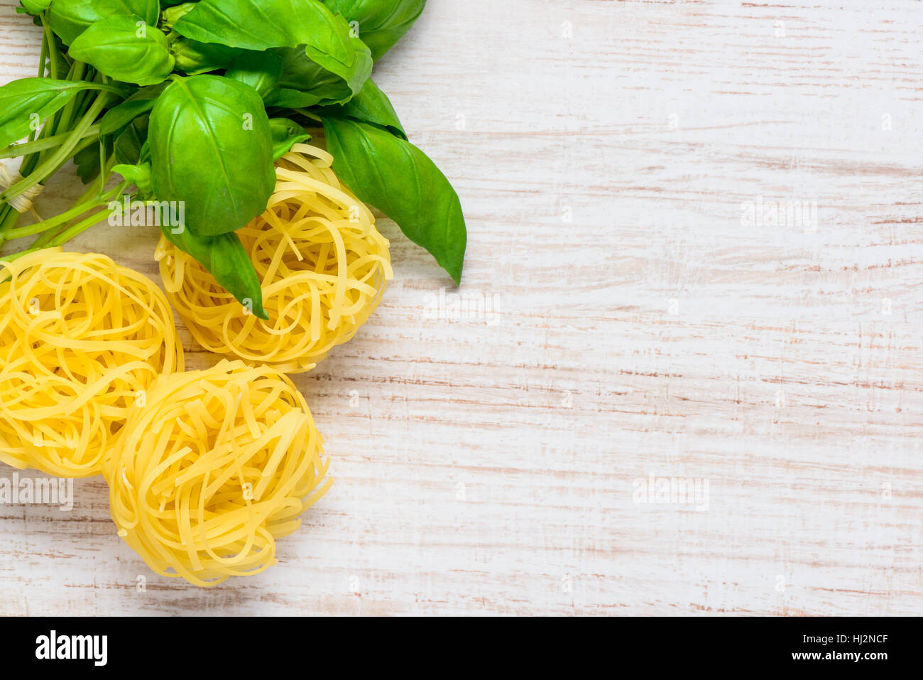 Copy Space with Fresh Green Basil and Yellow Tagliatelle Pasta in Top View Stock Photo