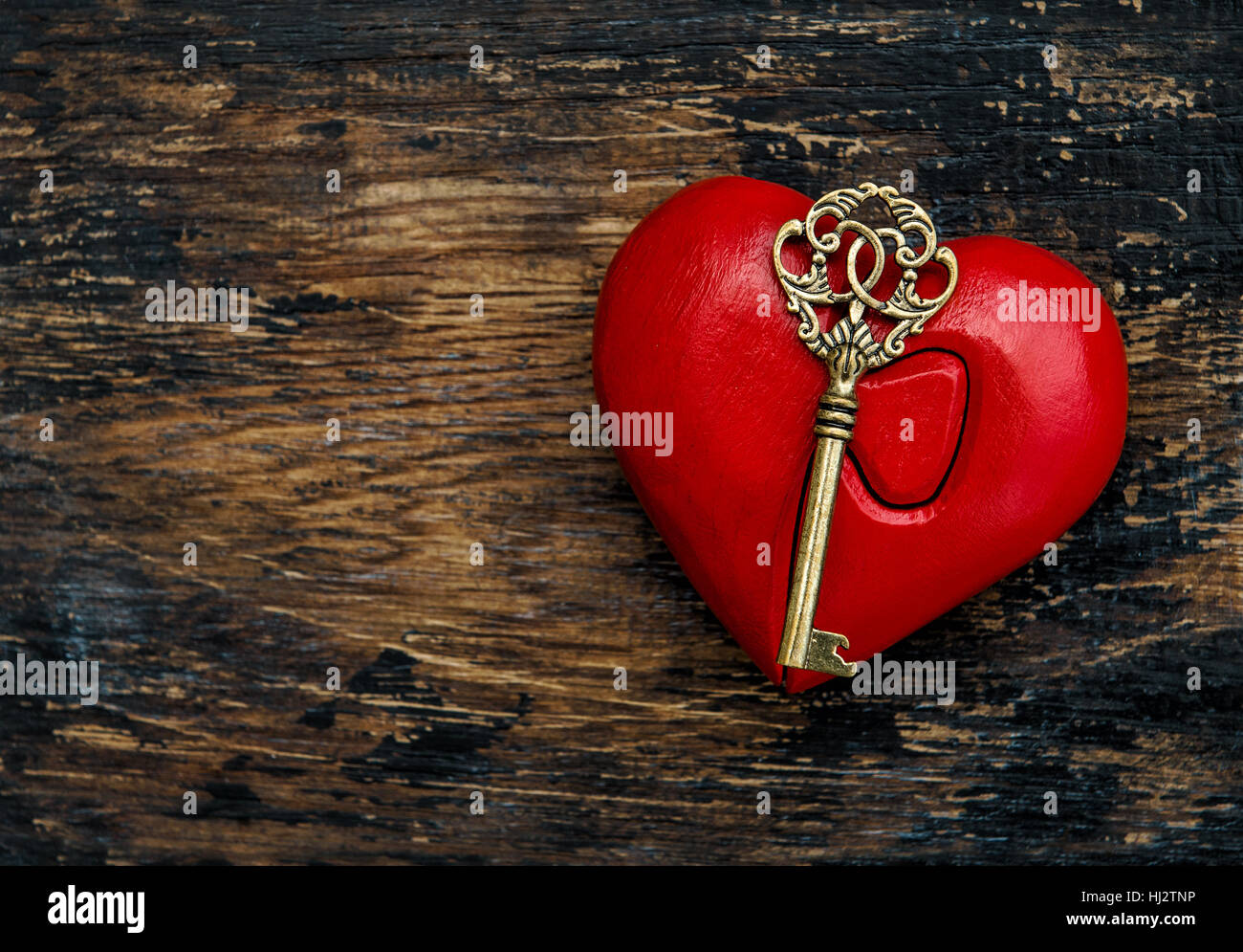 Red Heart with Golden Key On Rustic Wooden Background. Valentines Day Decoration Stock Photo