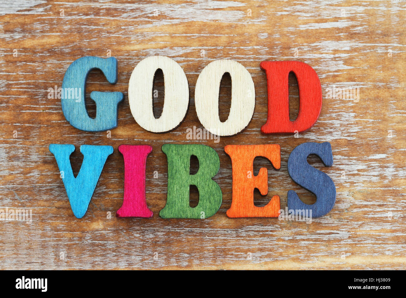 Good vibes written with colorful letters on rustic wooden surface Stock Photo