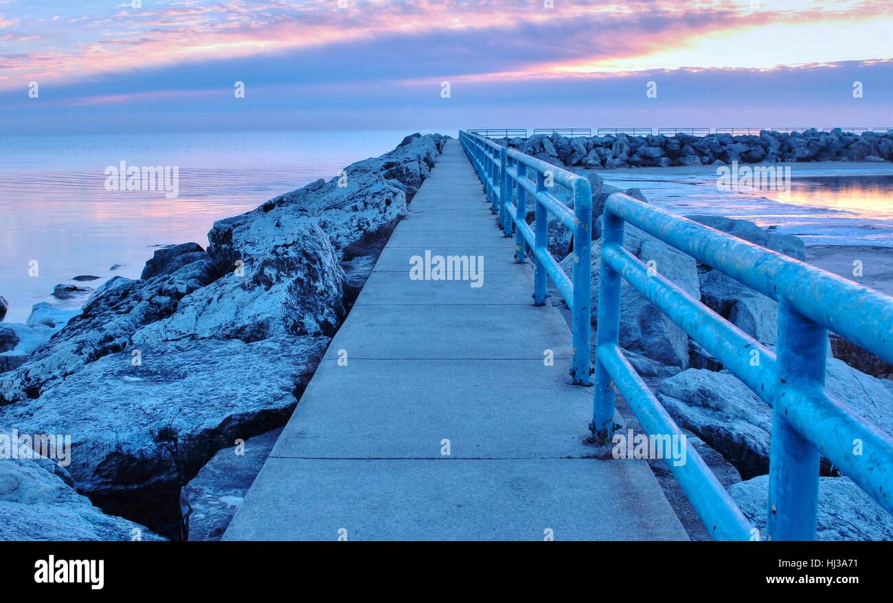 Soft sunrise colors reflect on Lake Huron, setting the tone for a beautiful morning walk. Lexington State Harbor. Lexington, Michigan. Stock Photo