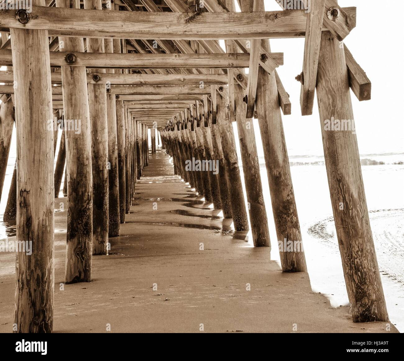 Coastal Living. Abstract view under long wooden pier with diminishing perspective along the Atlantic Ocean coast in Myrtle Beach, South Carolina, USA. Stock Photo