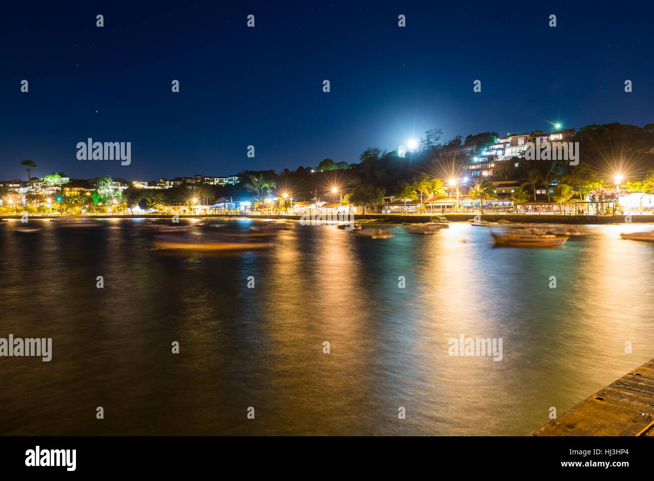 The city in twilight time with blurry boats and night lights on the background. Long exposure photo in Buzios, Rio de Janeiro State. Stock Photo