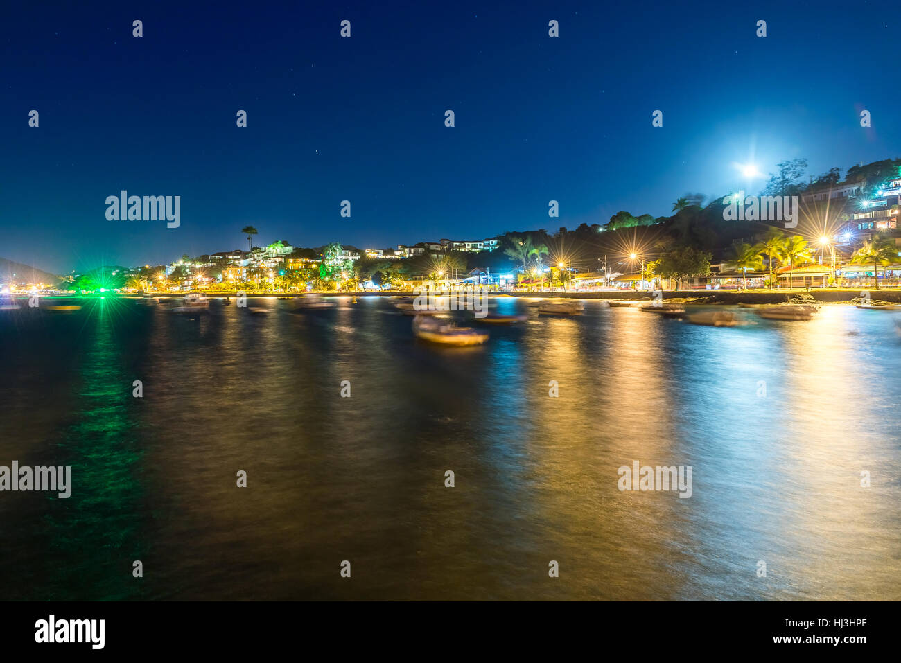 The city in twilight time with blurry boats and night lights on the background. Long exposure photo in Buzios, Rio de Janeiro State. Stock Photo