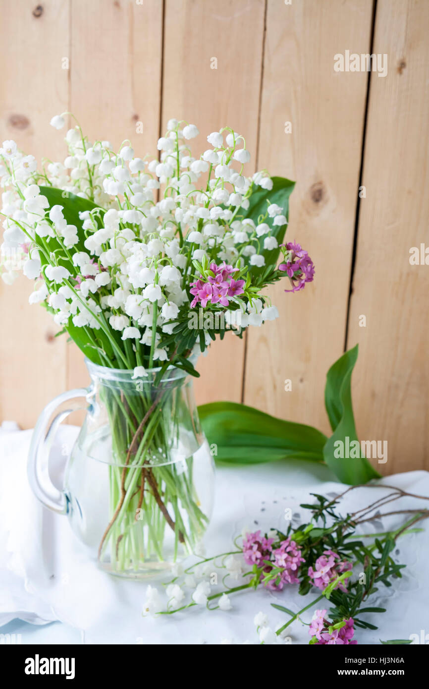 Beautiful bouquet white lily of the valley in a glass jar on a light ...