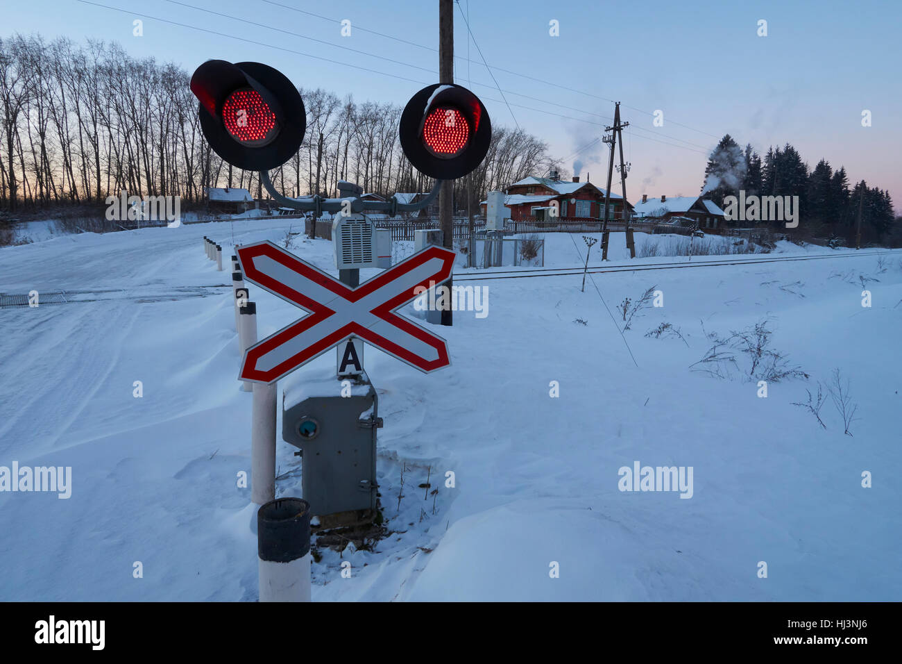 Red stop lights and road sign at railroad crossing. Ostashkovskiy district, Tver oblast, Russia, January 2017. Stock Photo