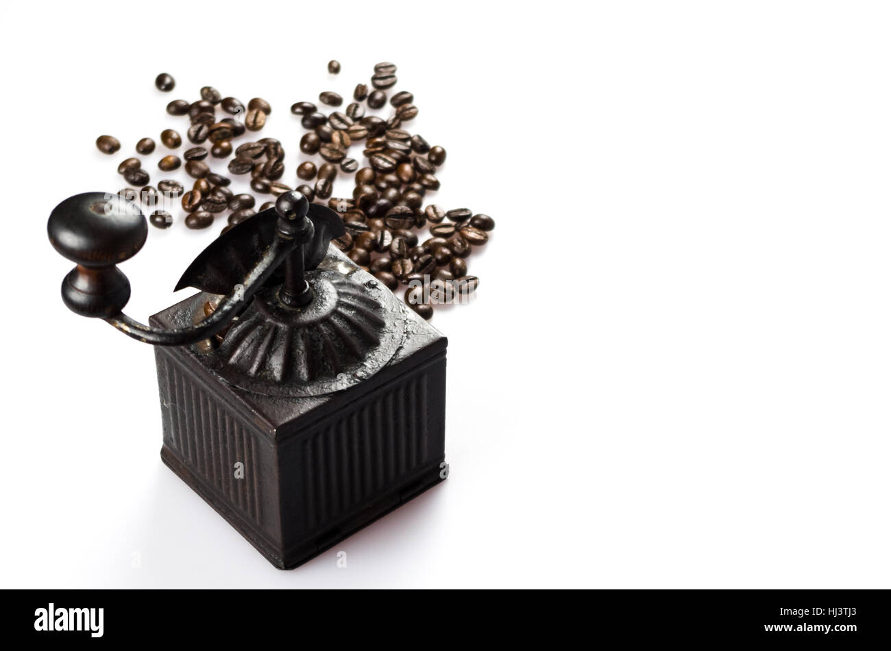 Close up of roasted coffee beans isolated on white background and an old coffee grinder Stock Photo