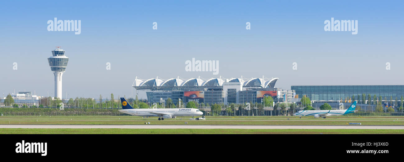 Panoramic view of Munich international airport with taxiing passenger airplanes and terminal and air traffic control tower Stock Photo