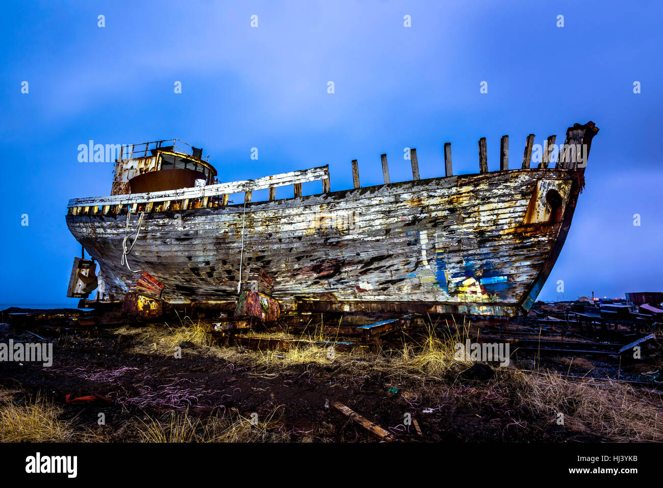 An old abandoned whaling ship from the early 1900's rests on a remote shipyard beach as it rots, exposing the ship's wooden ribs and hull infrastructu Stock Photo