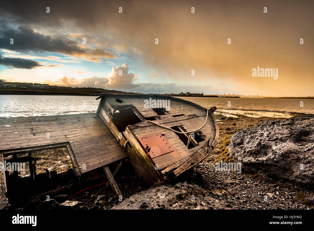 An old abandoned fishing vessel from the early 1900's rests on a remote beach as it rots, exposing the ship's wooden ribs and hull infrastructure. Stock Photo