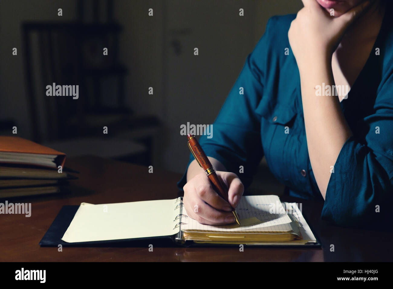 Young lady writing in her notepad late at night Stock Photo