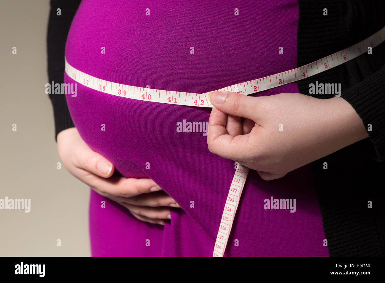 Pregnant mother using a tape measure to check her tummy Stock Photo Alamy