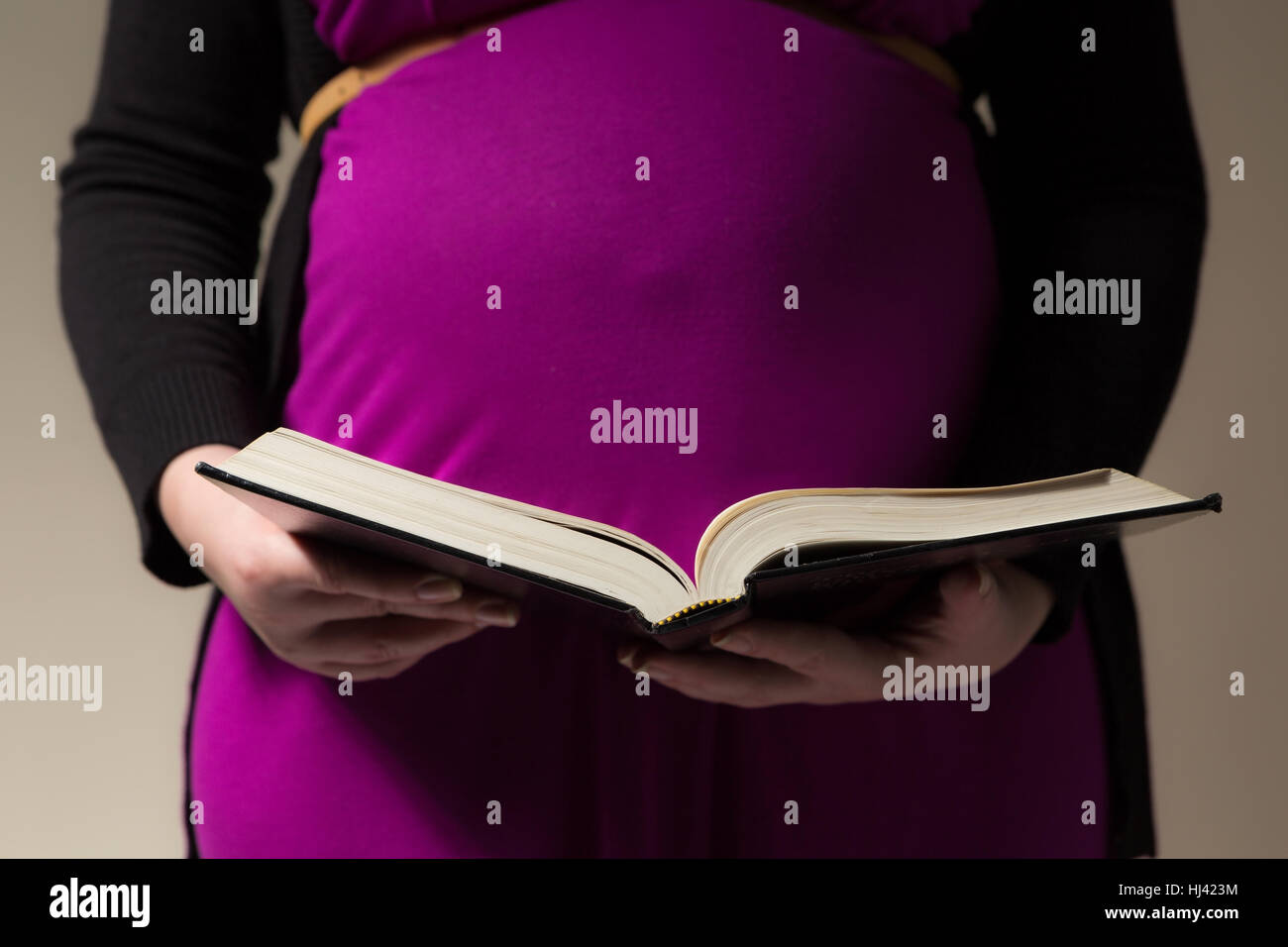 Pregnant mother reading the KJV Bible to her unborn child Stock Photo
