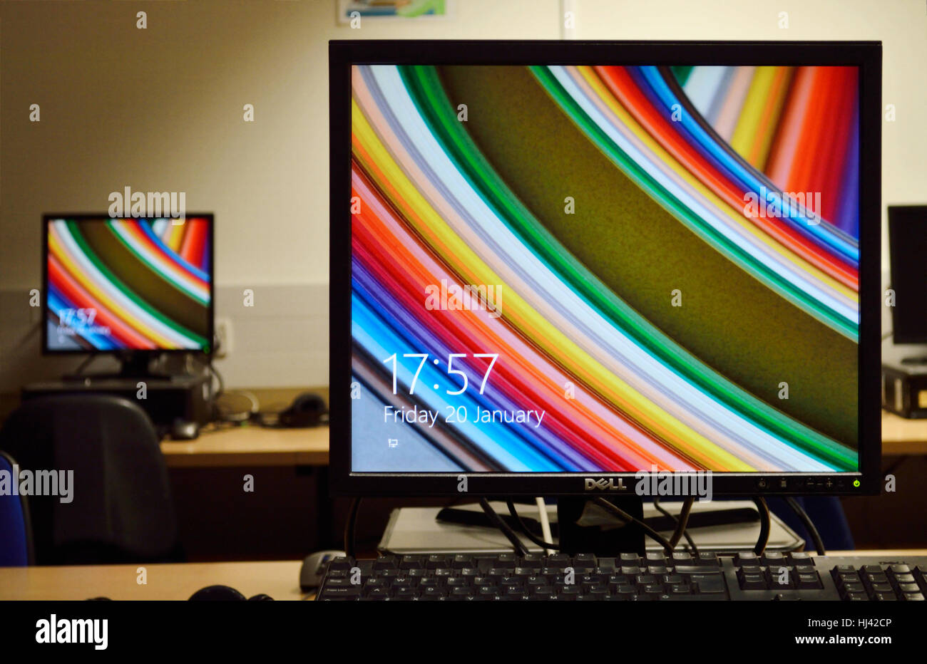 Two computer monitors with screen savers in a classroom at a school. Stock Photo