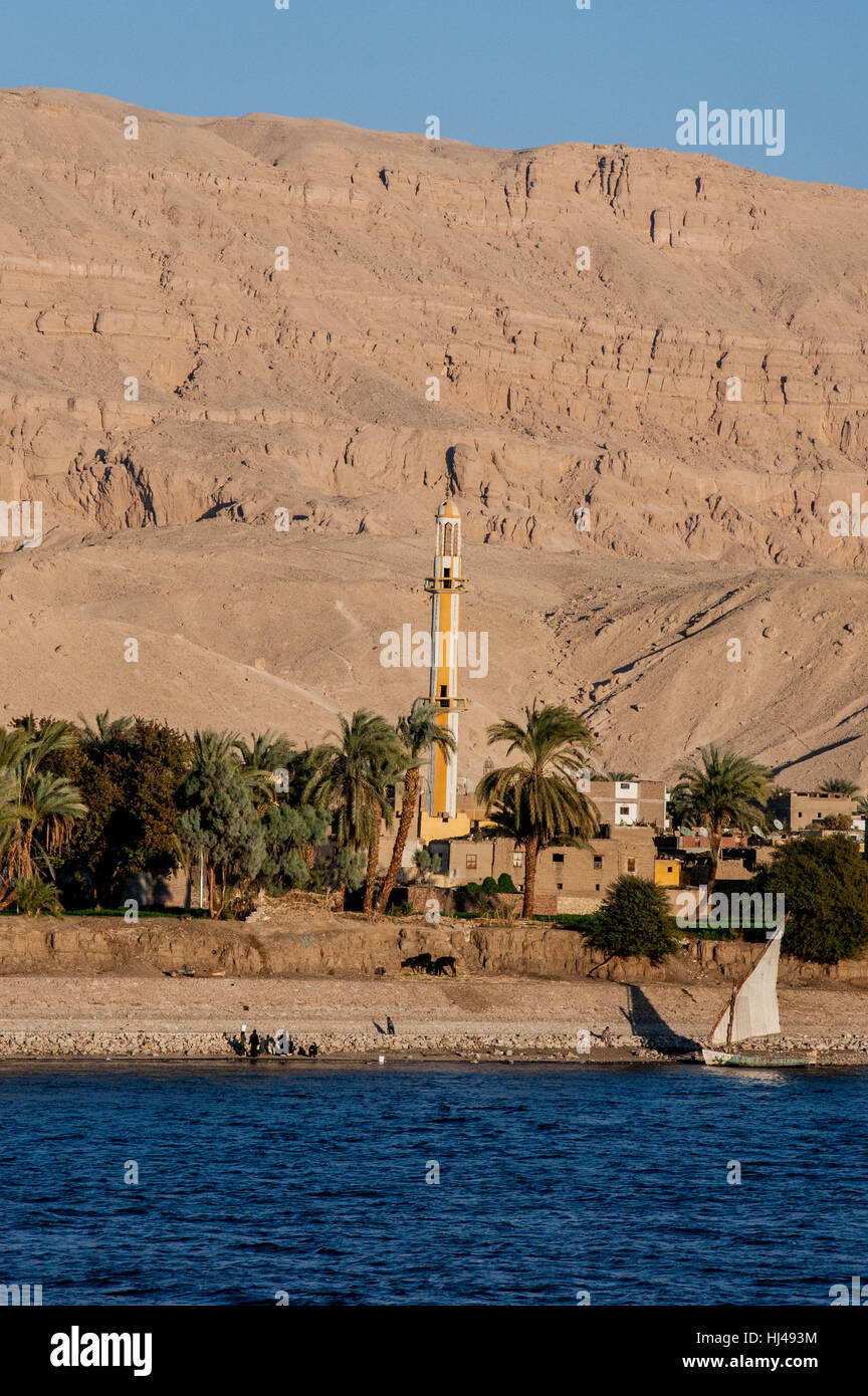 Life along the Nile River, Egypt, with minaret, sailboat and the houses clustered around it. Stock Photo