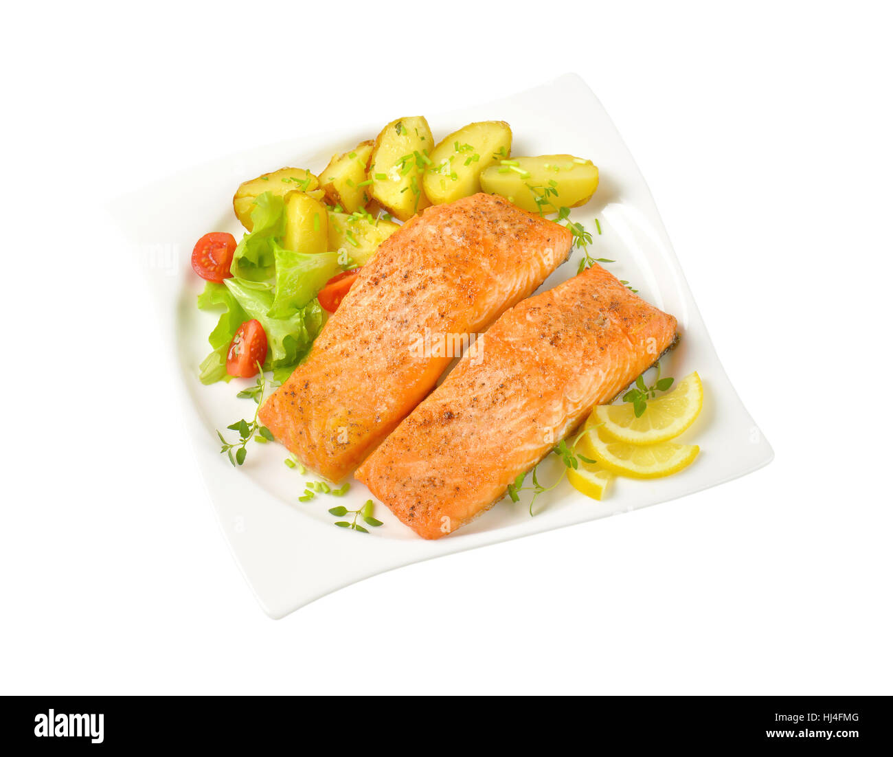 salmon fillets with roasted potatoes and vegetable garnish on square plate Stock Photo