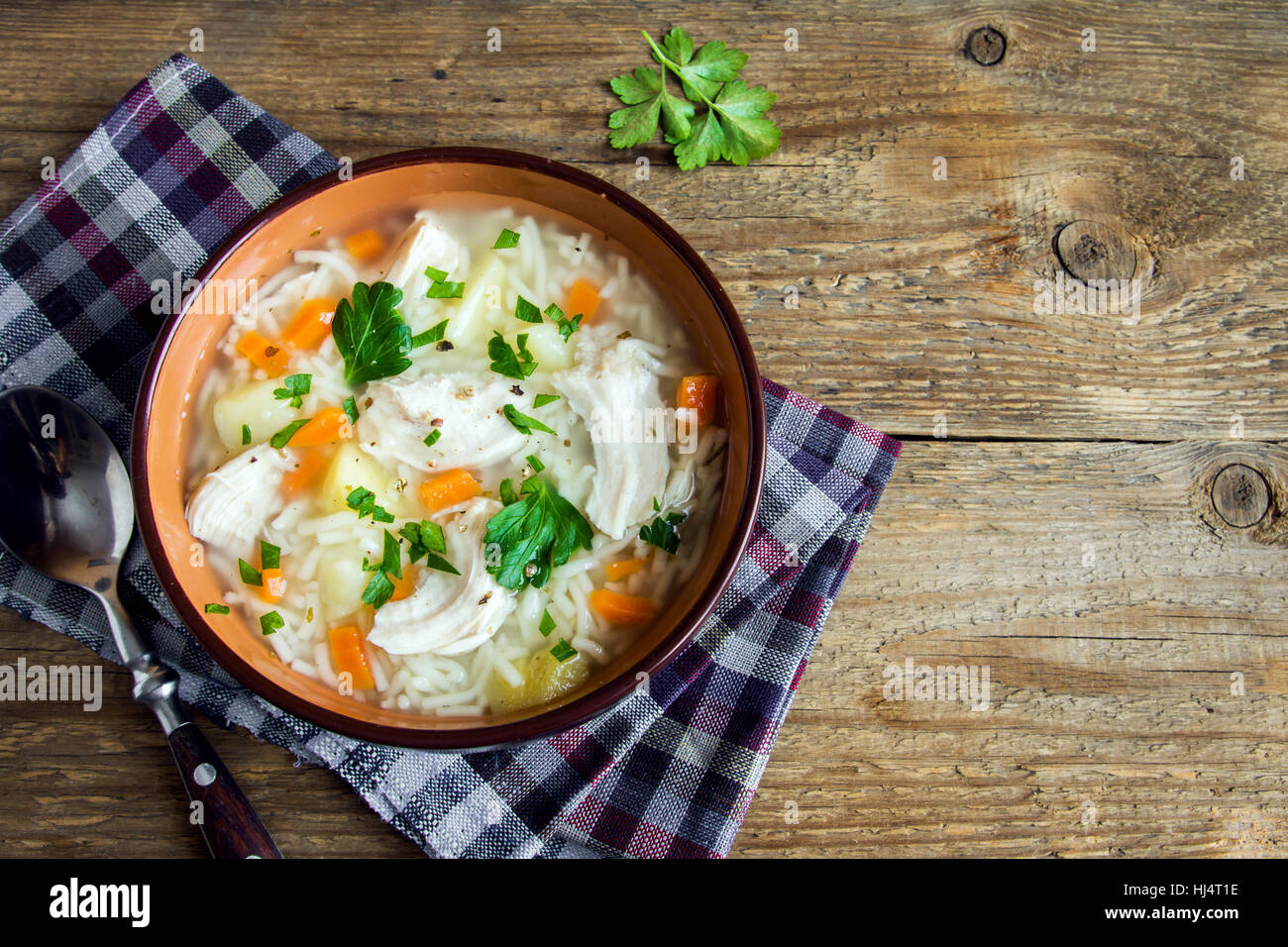 Chicken soup with noodles and vegetables in bowl over rustic wooden background - homemade healthy meal Stock Photo