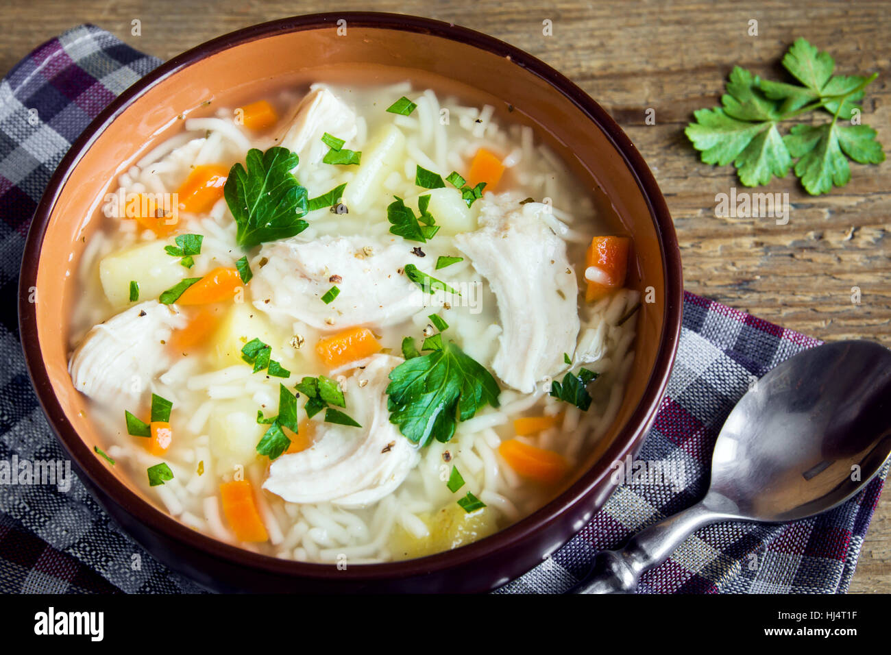 Chicken soup with noodles and vegetables in bowl over rustic wooden background - homemade healthy meal Stock Photo