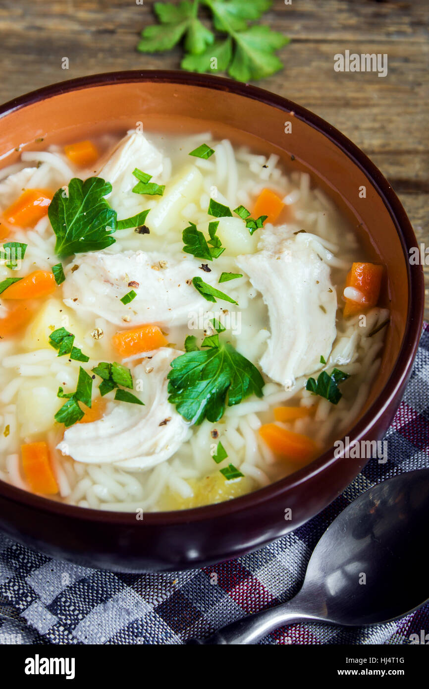 Chicken soup with noodles and vegetables in bowl over rustic wooden background - homemade healthy meal Stock Photo