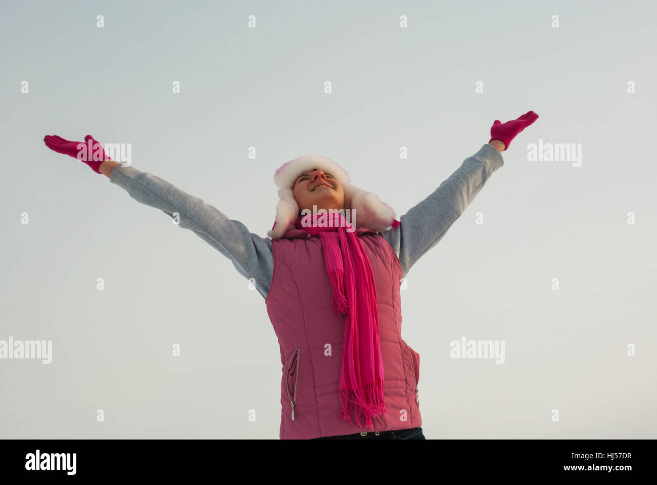 Teen girl staying with raised hands against blue sky Stock Photo - Alamy