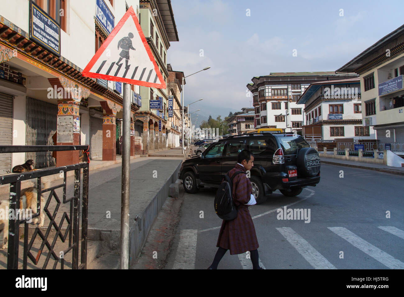 Pedestrian in traditional gho crossing on main street (Norzin Lam) in Thimphu, Bhutan. Stock Photo