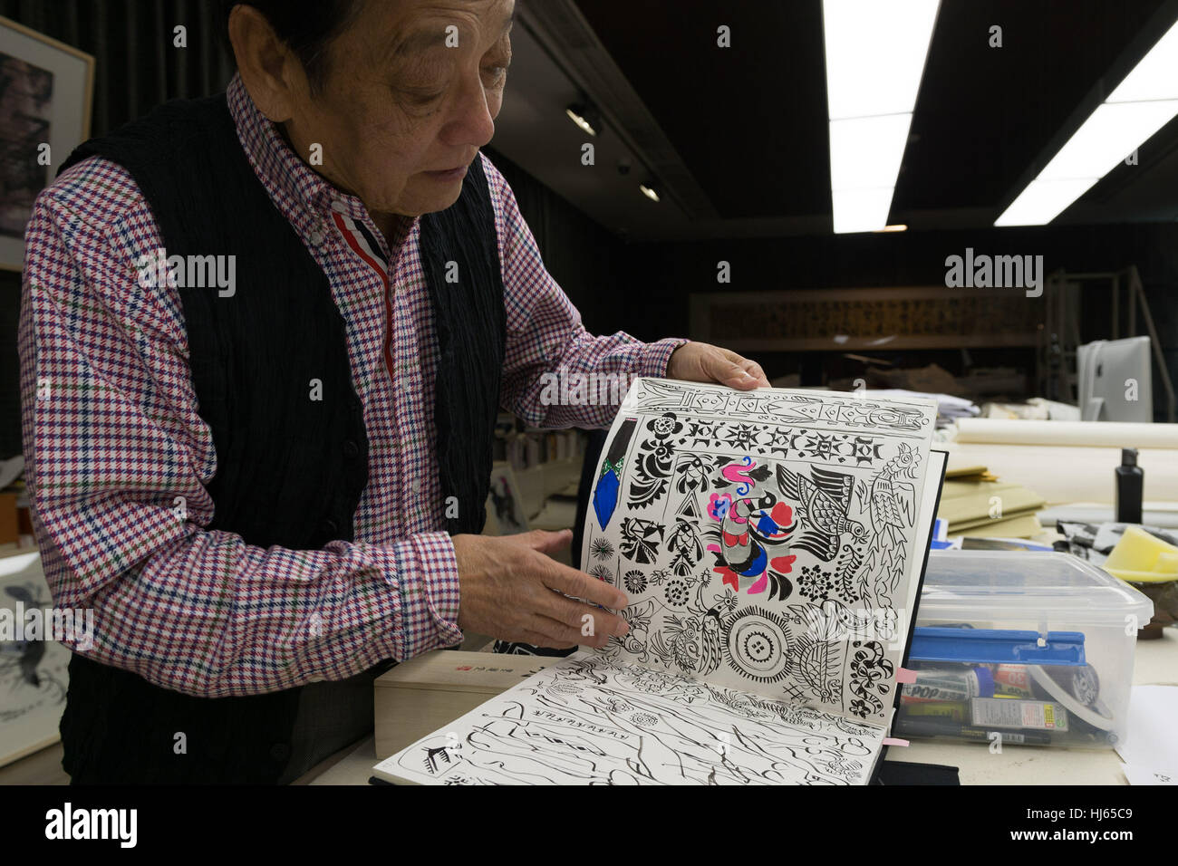 (170126) -- BEIJING, Jan. 26, 2017 (Xinhua) -- Chinese artist Han Meilin, 80, shows his sketches at his studio in eastern district of Tongzhou in Beijing, capital of China, Jan. 24, 2017. Han, designer of the 2008 Beijing Olympic Games mascot 'Fuwa,' has just finished the design of Chinese zodiac stamps for the upcoming Year of the Rooster. The set of Chinese Lunar New Year rooster stamps, issued earlier this month, contain two items showing a rooster striding proudly and a hen looking after her two chicks. Han applied rich color and elements of traditional Chinese painting to depict a happy f Stock Photo