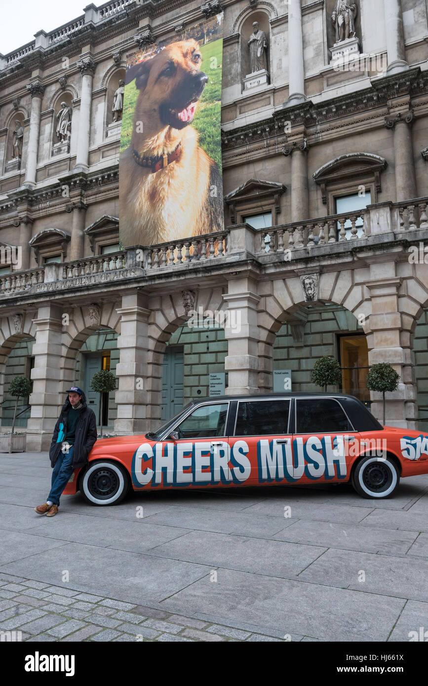 London, UK.  26 January 2017.  Student Thomas Langley stands next to his work 'Chavy boy', a decorated Daimler XJ6.  Behind him is 'German Shepherd for Burlington House', an 11m banner, by Gina Fischli, both on display at 'Premiums Interim Projects', an exhibition of new work by 13 second year students at the Royal Academy, Piccadilly, who are at the interim point of their postgraduate study at RA Schools, the UK's longest established art school. © Stephen Chung / Alamy Live News Stock Photo