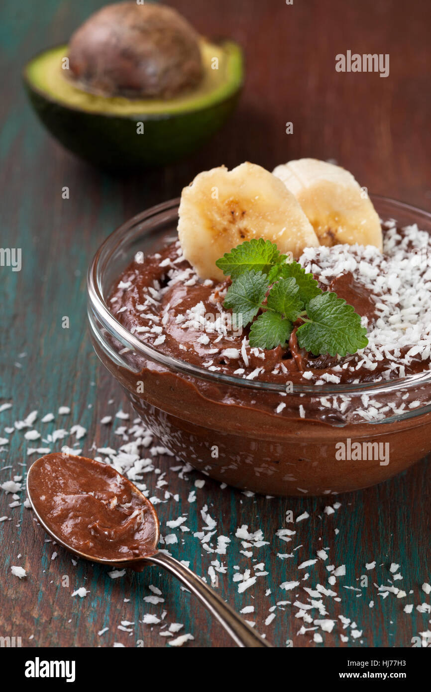 raw vegan avocado banana pudding with coconut crumbs in a glass bowl