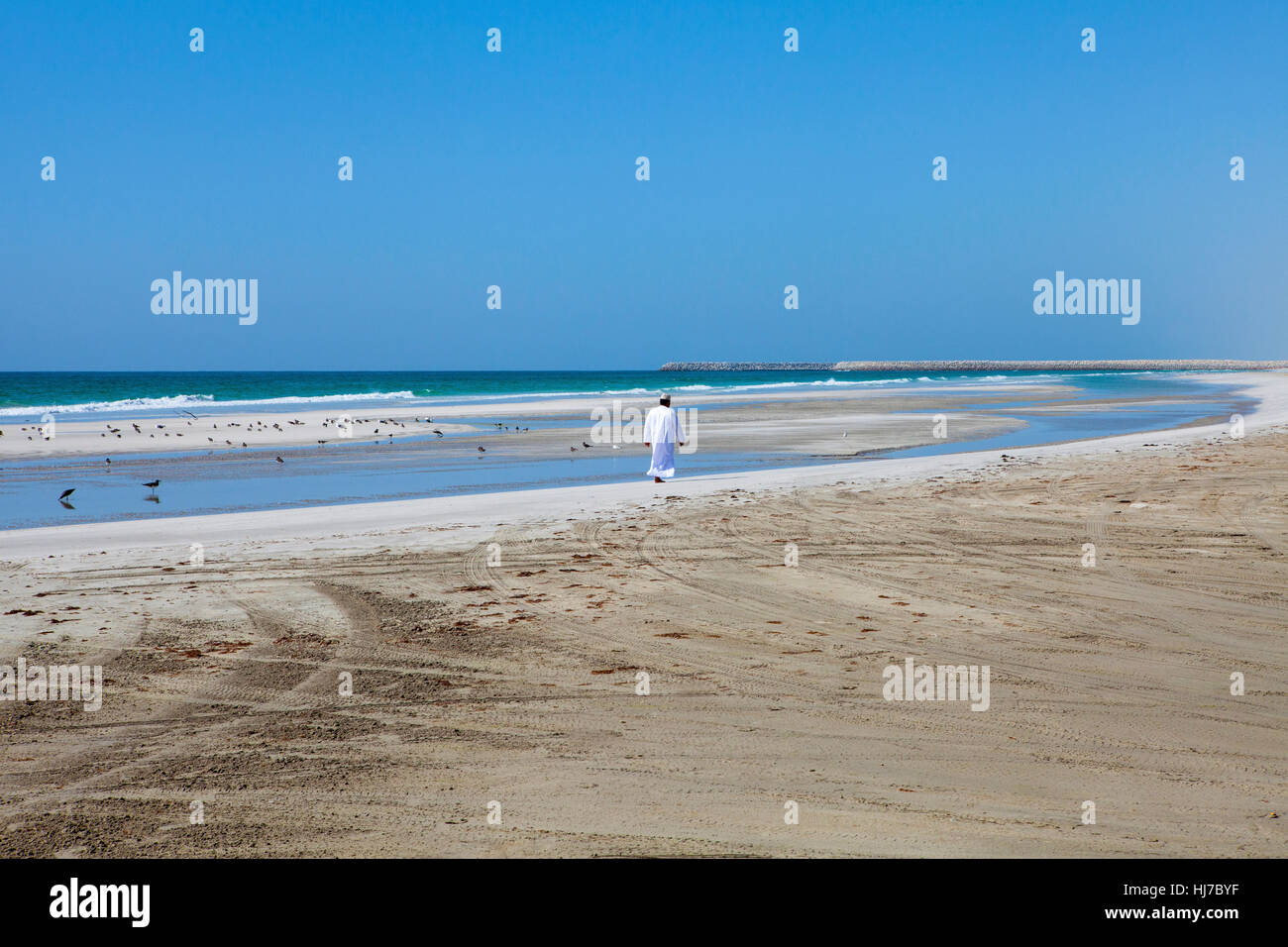 Omani man walking along the beautiful Indian Ocean coast. Stock Photo