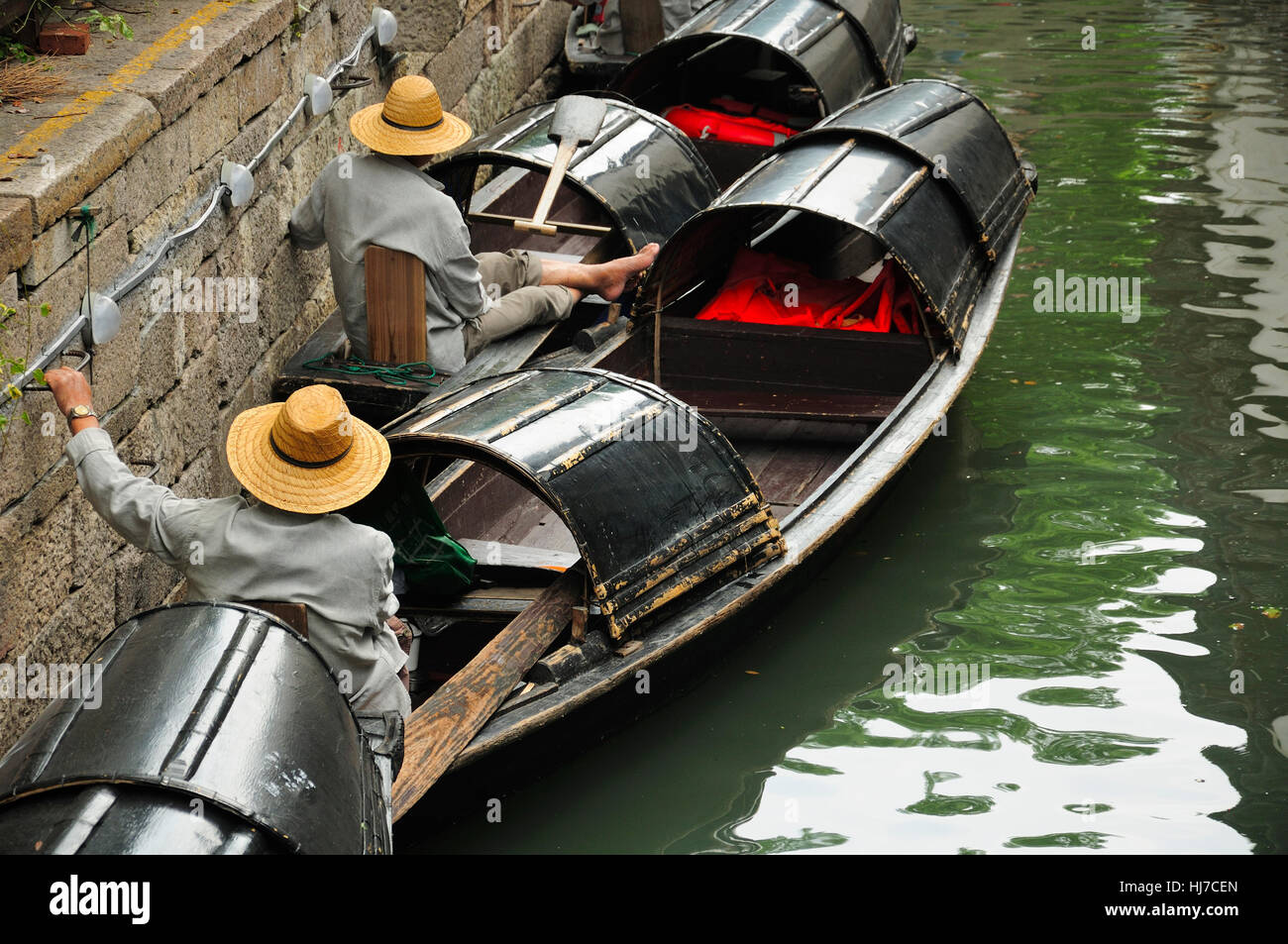 Chinese oarsmen sitting in the wu peng chuan or the black canopied boats on the canals of Lu Xun native place in the city of Shaoxing China Stock Photo
