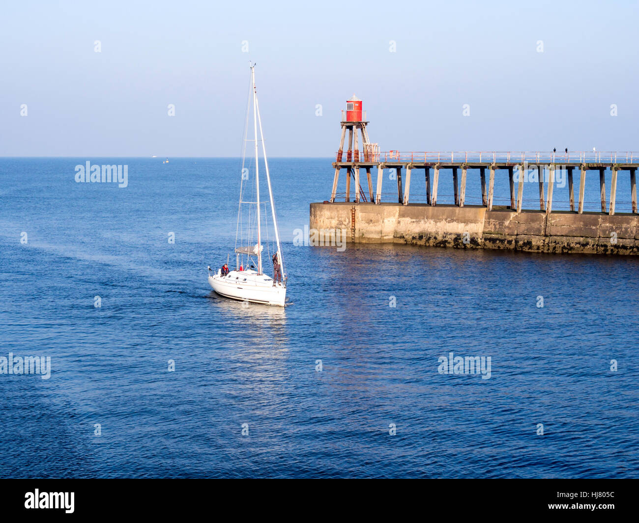 A sailing yacht arriving in Whitby harbour under power on a sunny ...