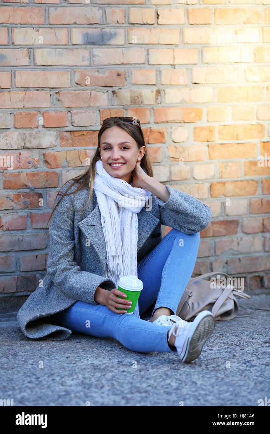 Smilling young woman near brick wall Stock Photo - Alamy