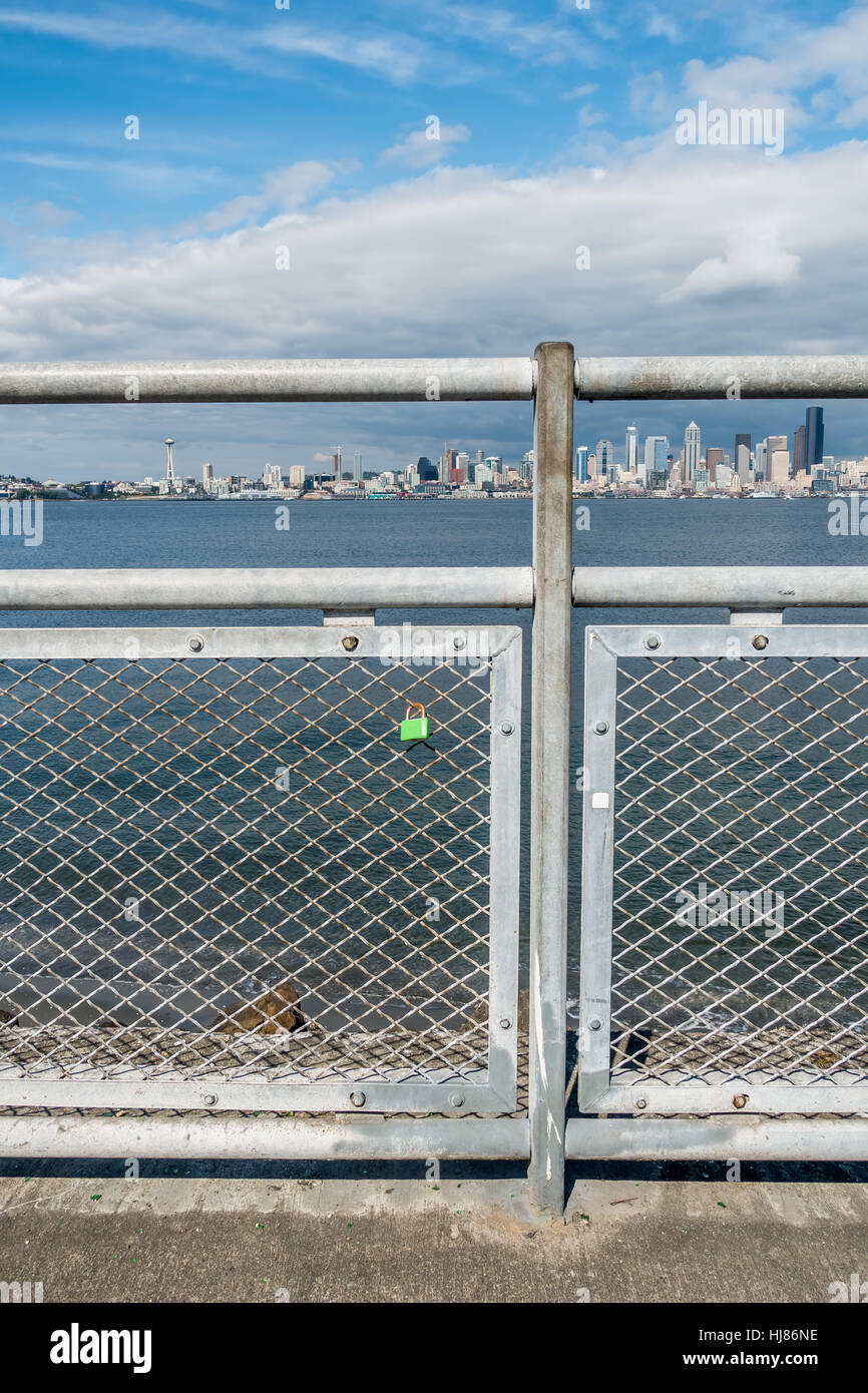 One green lock hangs on a fence with the Seattle skyline in the background. Stock Photo